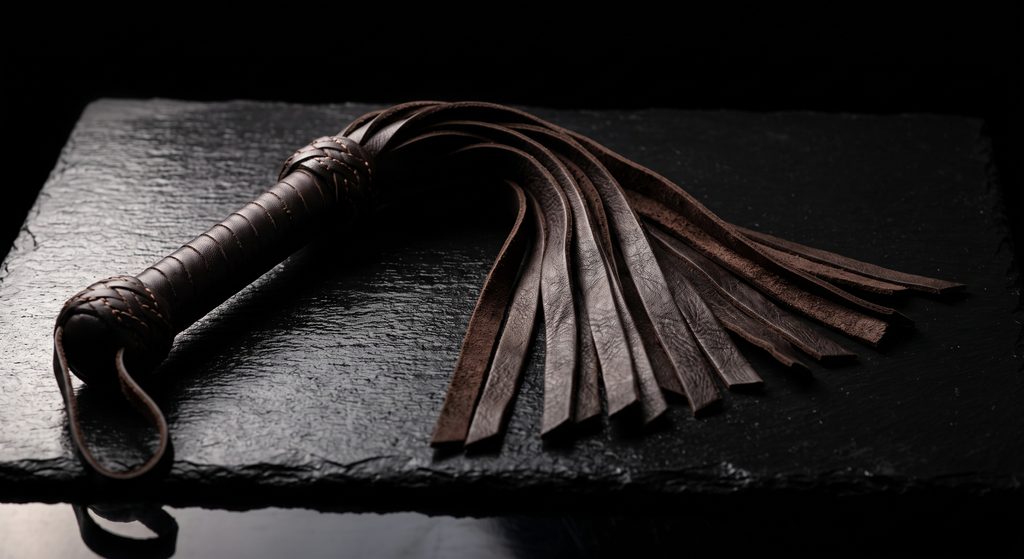impact play, martinet de cuir aux lanières ouvertes sur ardoise sombre