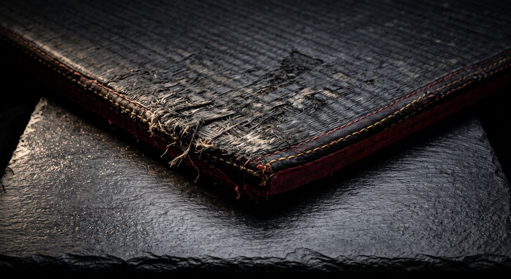 rôle de proie BDSM, coin de tatami usé sur ardoise sombre